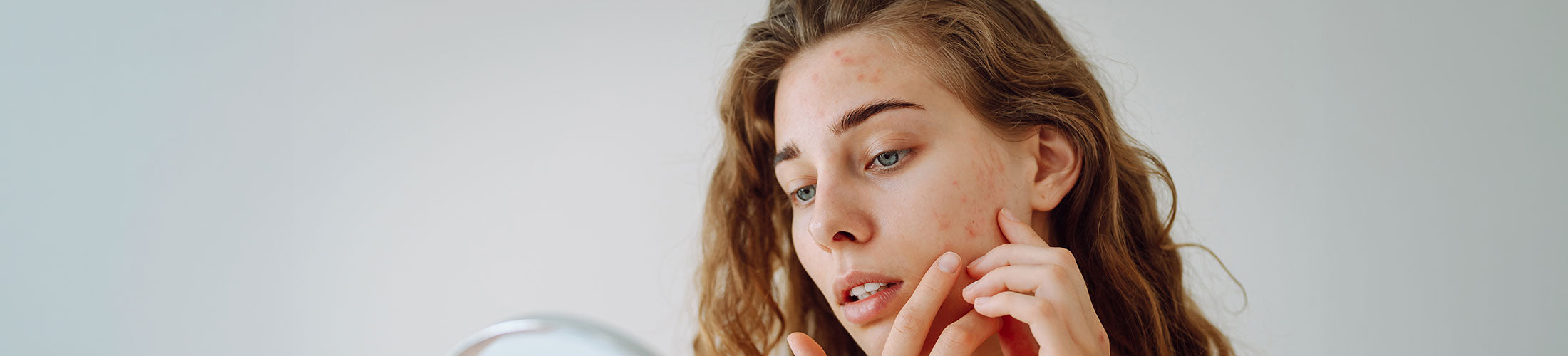 Woman applying lipstick in front of a mirror with a neutral background