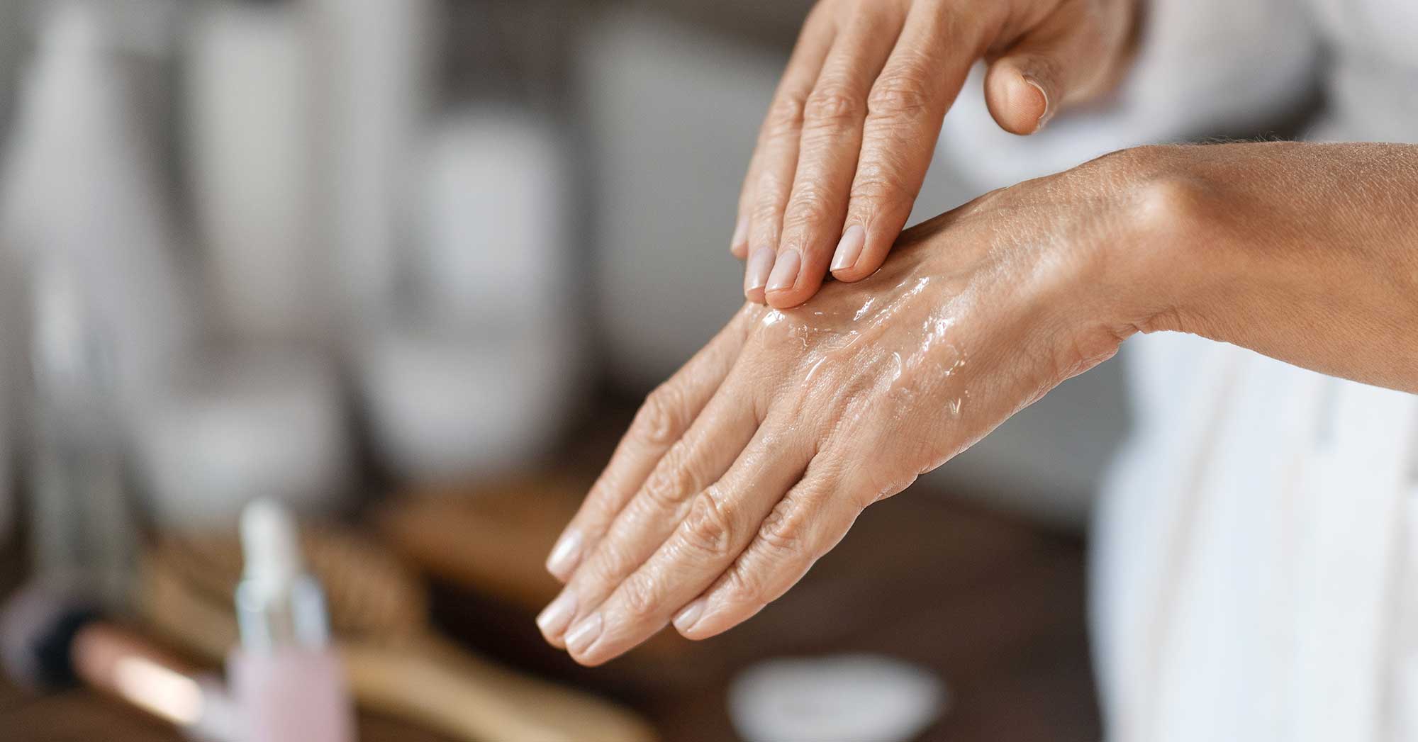 Person applying lotion to hands with a blurred background